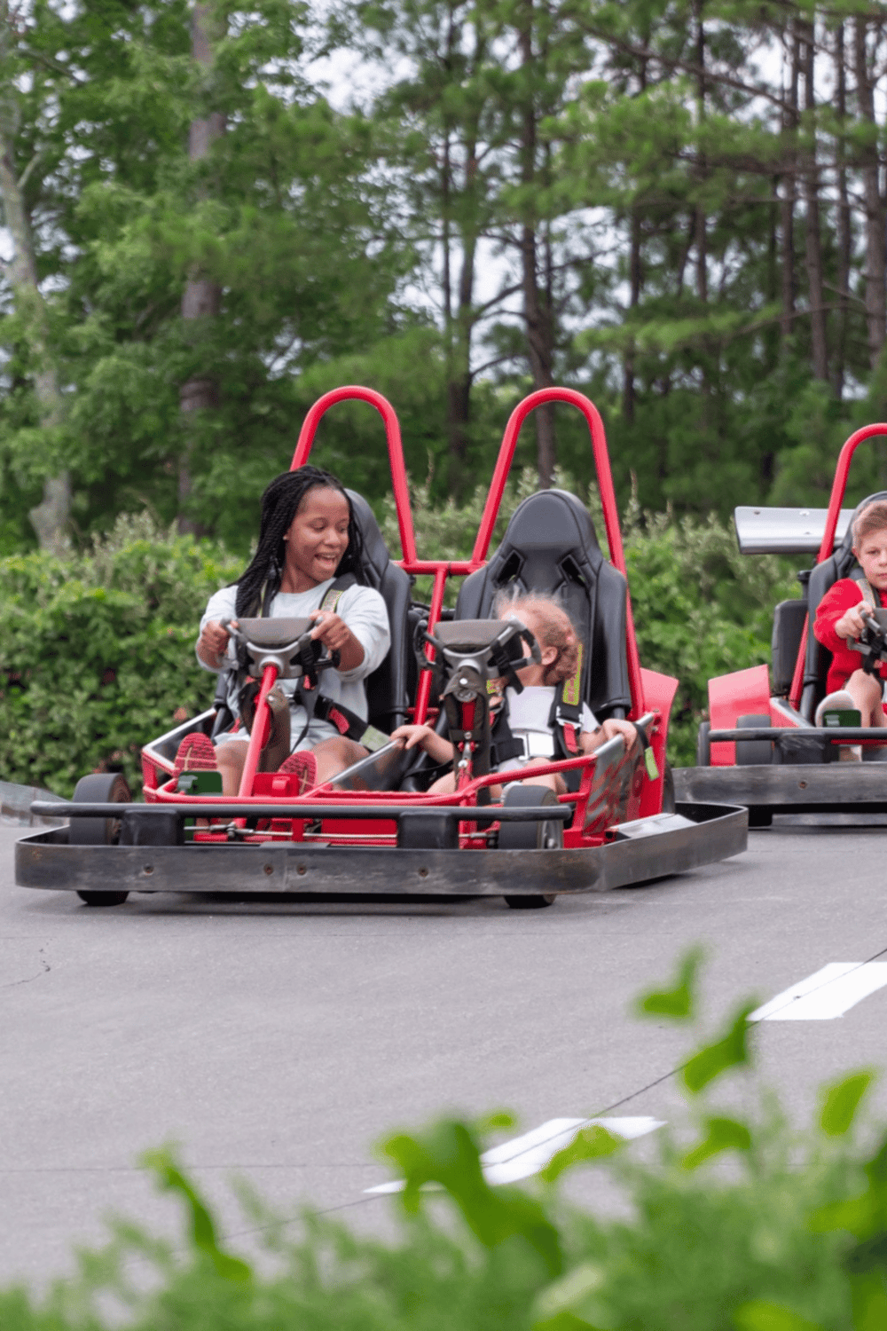 Kids enjoying go-kart racing at Quest for Directions outdoor adventure park.
