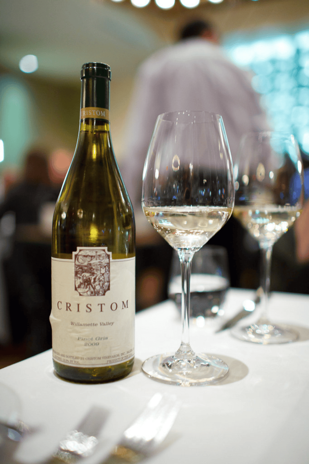Luxurious white wine bottle and glasses at elegant restaurant table for fine dining experience.