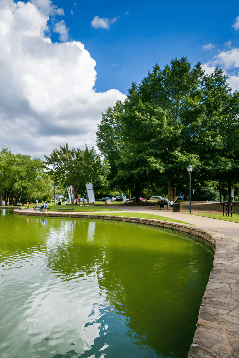 Beautiful park with water feature, lush trees, and walking paths for outdoor recreation.