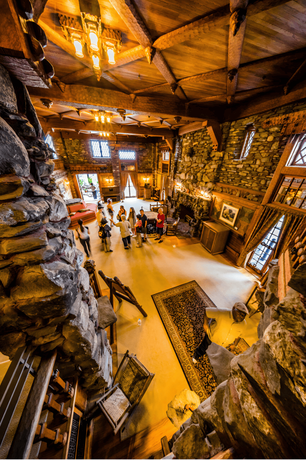 Cozy lodge interior with stone walls, wooden beams, and gathering of people in a rustic setting.