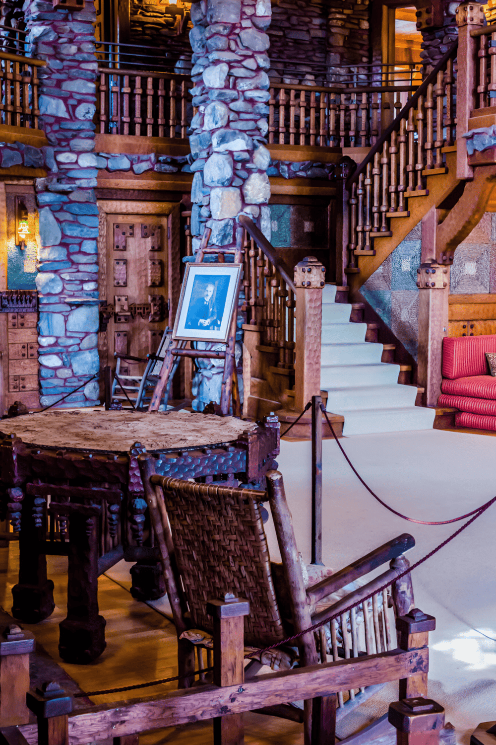 Handcrafted rustic lodge interior with stone pillars, wooden stairs, and cozy seating for adventure travelers.