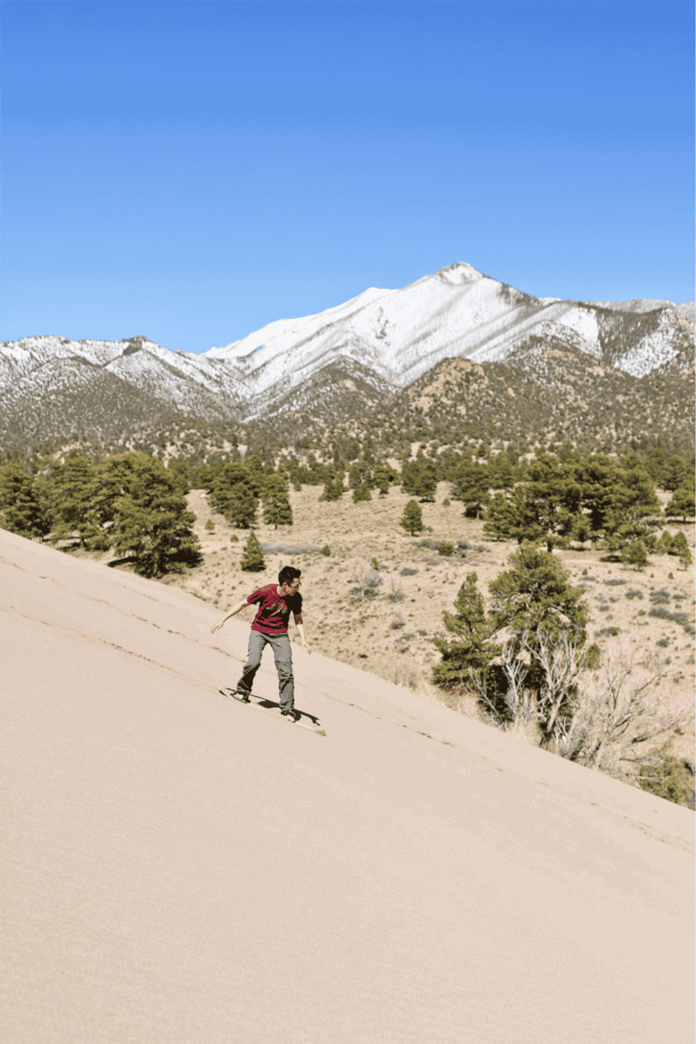 Bright kid skateboarding on sand dune with snowy mountains in background, adventure, outdoor recreation, QuestForDirections.