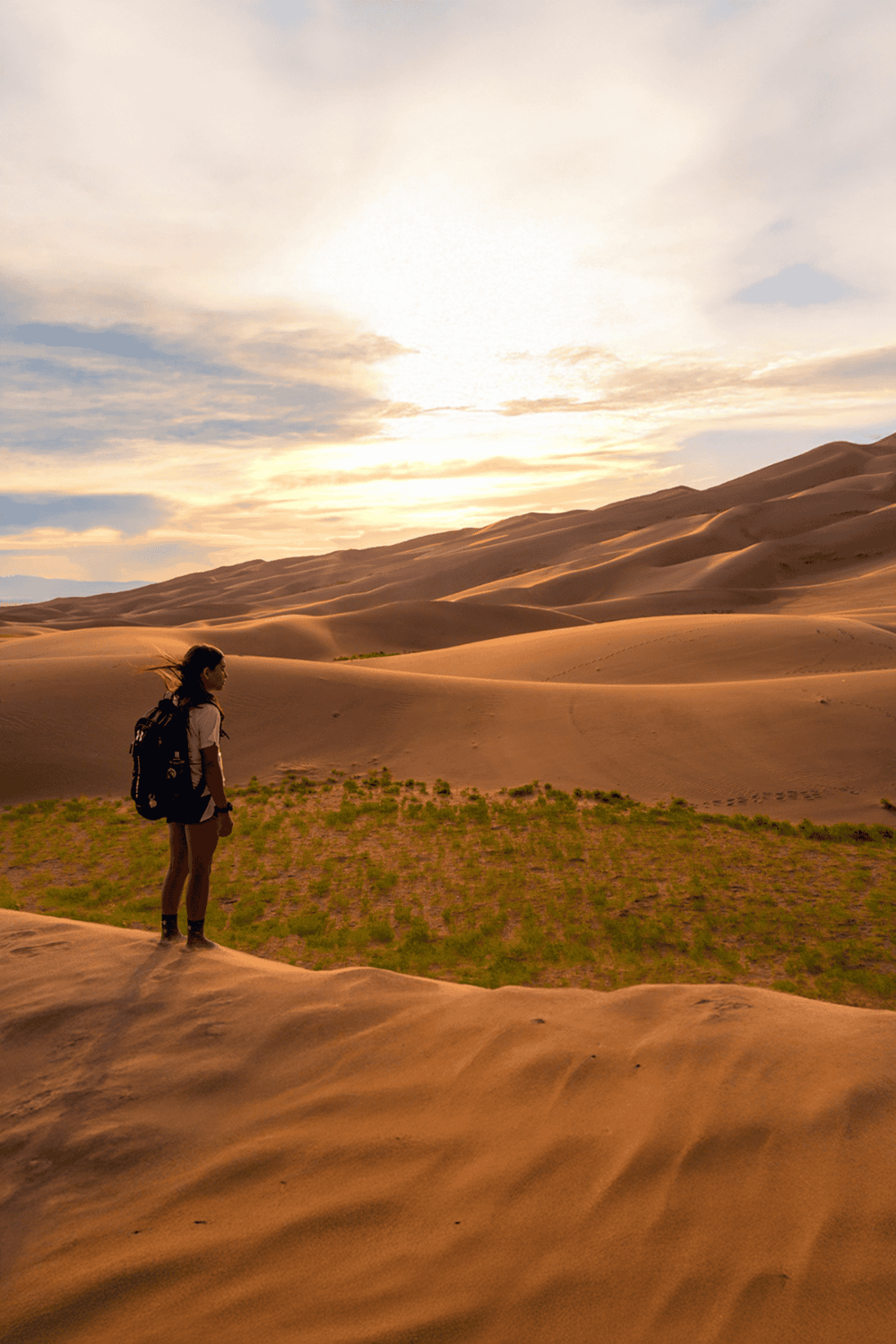 Desert hiking adventure with a solo traveler exploring sand dunes at sunset.