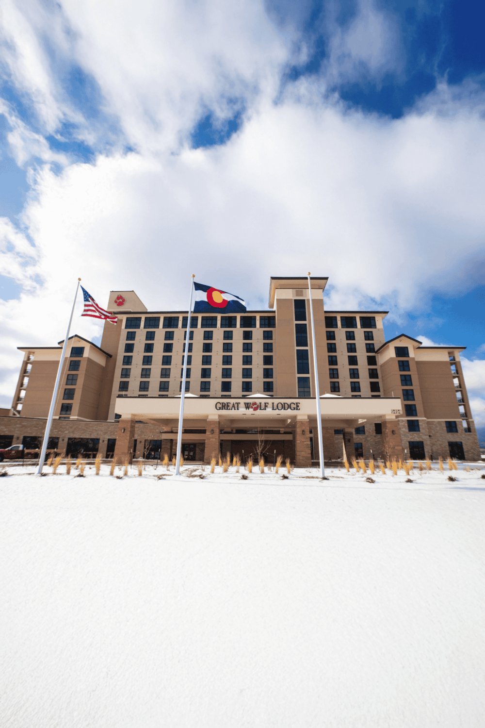 Flagged building at QuestForDirections hotel with Colorado and U.S. flags, under a partly cloudy sky.