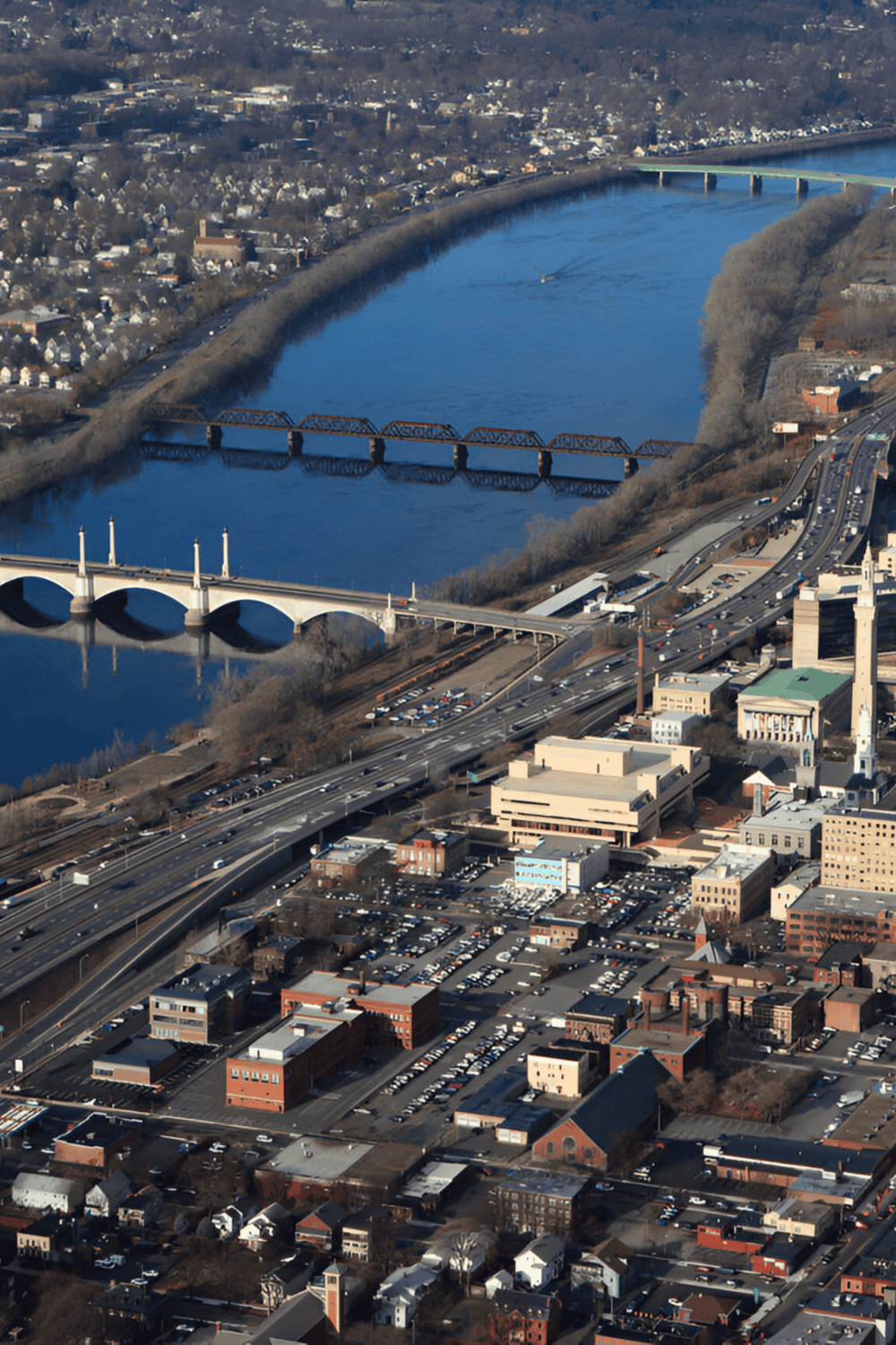Aerial view of a city with a winding river and multiple bridges, showcasing urban infrastructure and transportation routes.