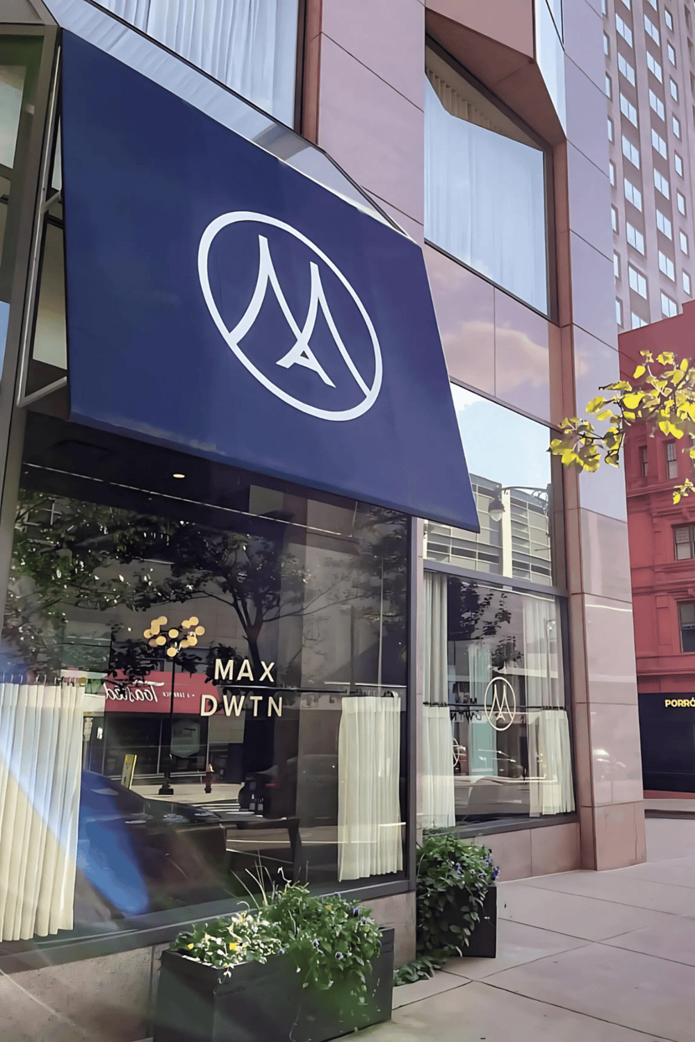 Blue logo sign for Max DWNT restaurant or cafe in downtown city street area.