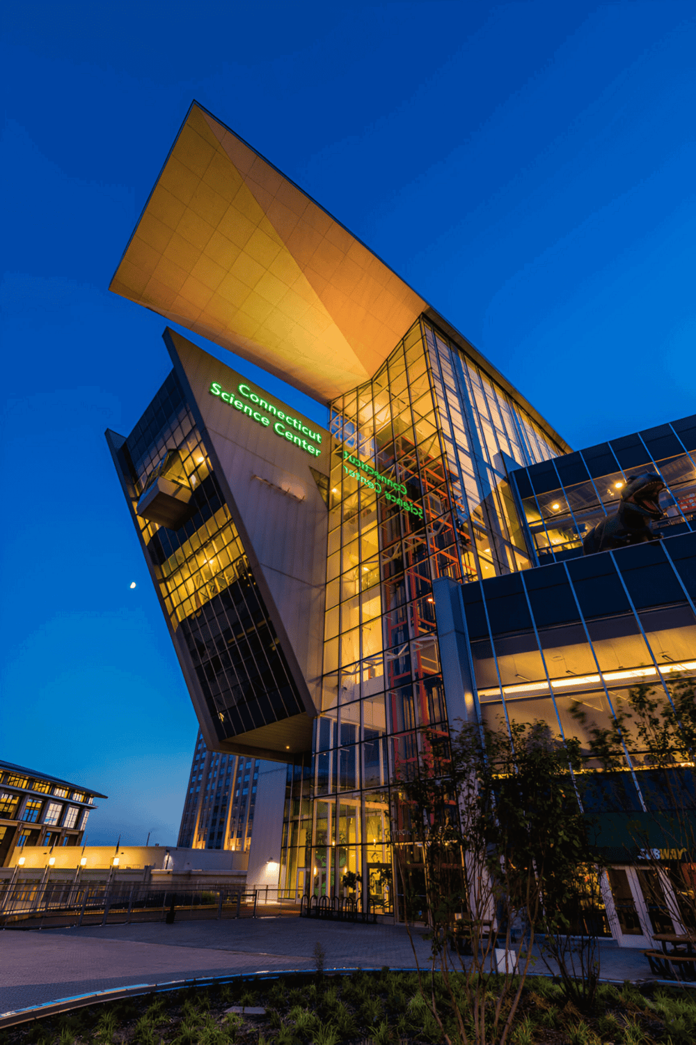 Futuristic Connecticut Science Center building illuminated at dusk with modern glass architecture.