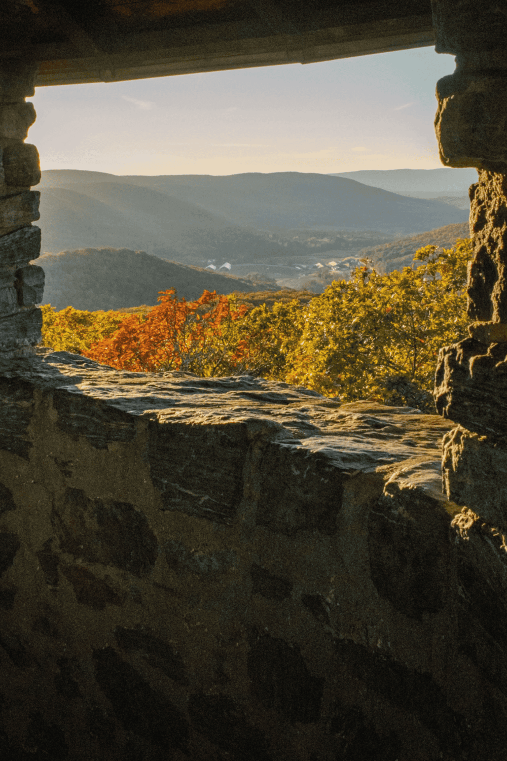 View of mountain landscape through stone window, autumn foliage, scenic outdoor view, travel, nature, exploration.