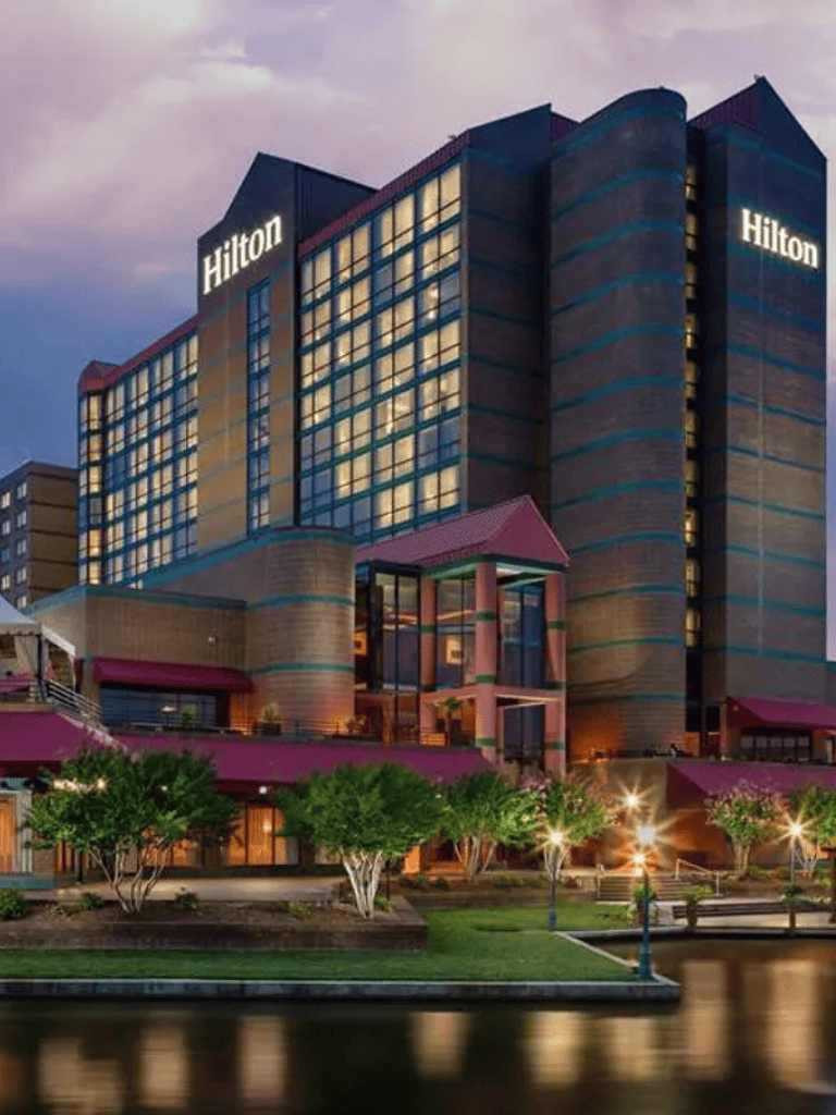 Luxury Hilton hotel downtown, night view with city lights and waterfront, modern architecture, travel destination, QuestForDirections.