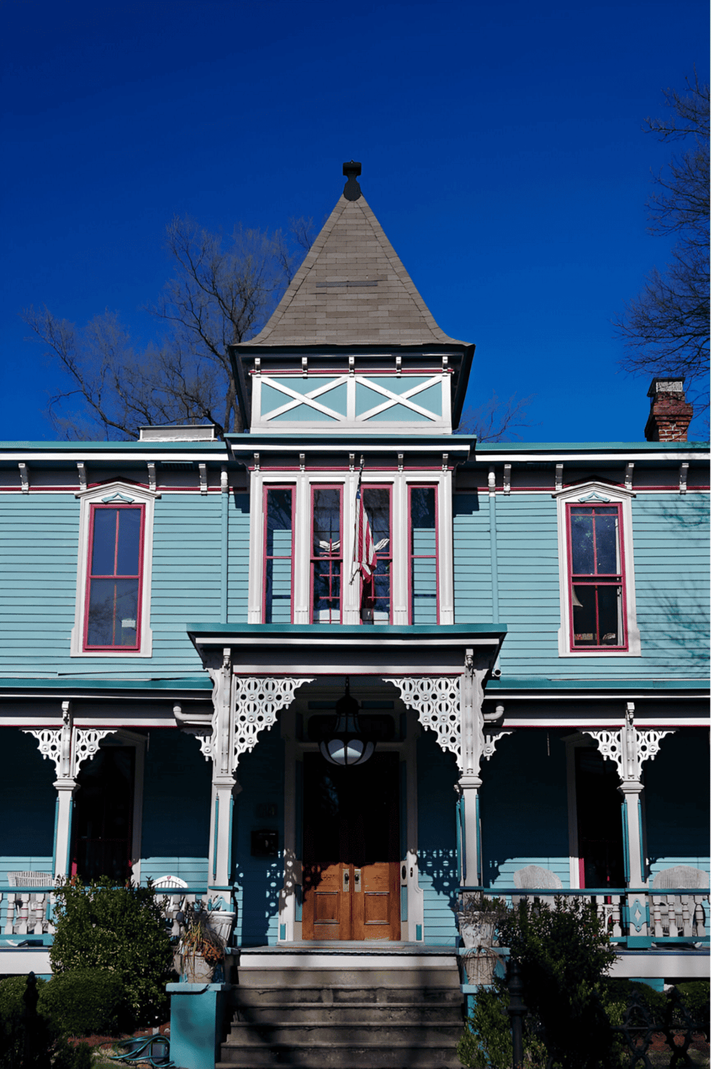 Victorian-style blue house with intricate trim and tower, showcasing historic architecture and charming curb appeal.