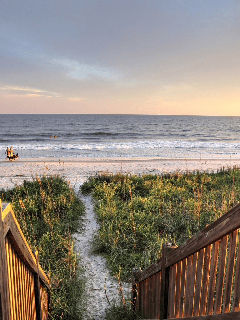 Beach access pathway leading to ocean sunset, scenic coastal view, relaxing seaside scenery.