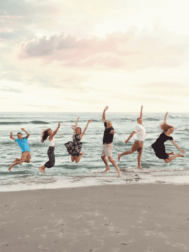 Happy family jumping on the beach with ocean background for travel and vacation planning.