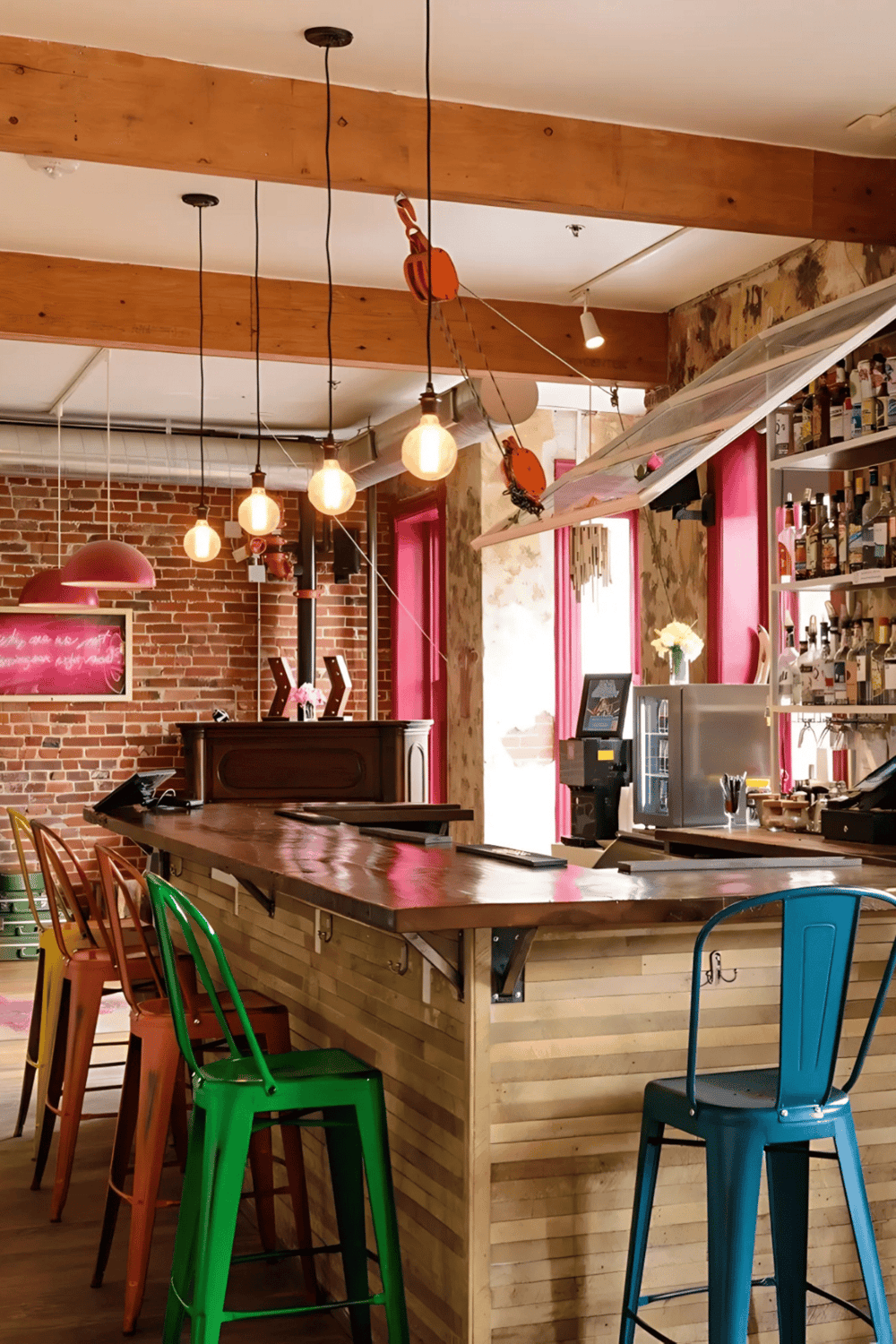 Colorful bar stools in a modern cafe with exposed brick wall and hanging lights, creating cozy ambiance.