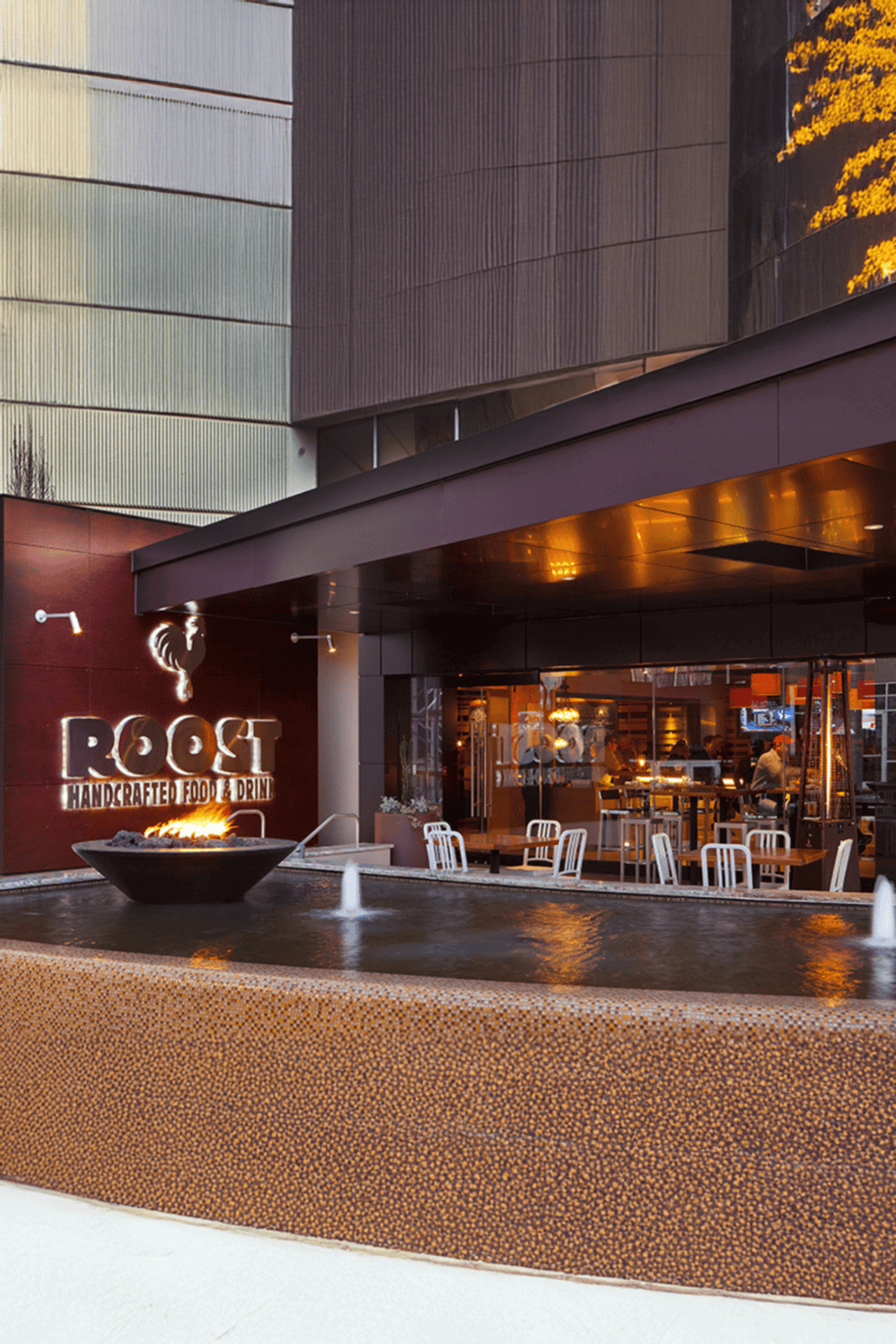 Cozy modern restaurant outdoor seating with water fountain and warm lighting.