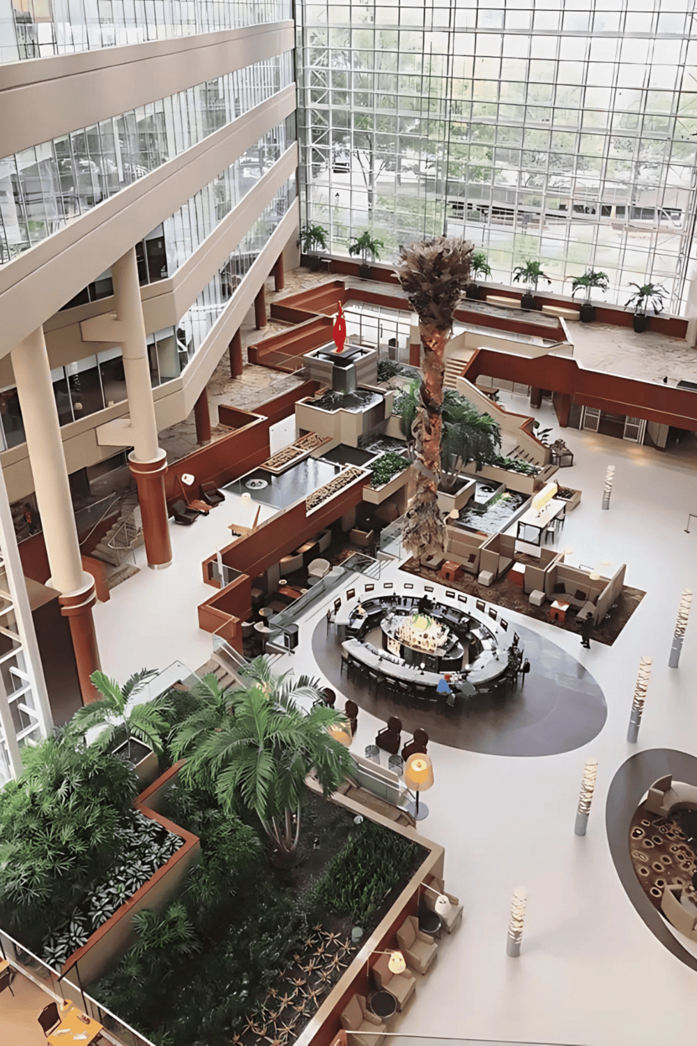 Luxurious hotel lobby with indoor garden, modern decor, and glass walls, perfect for travelers seeking comfort and style.