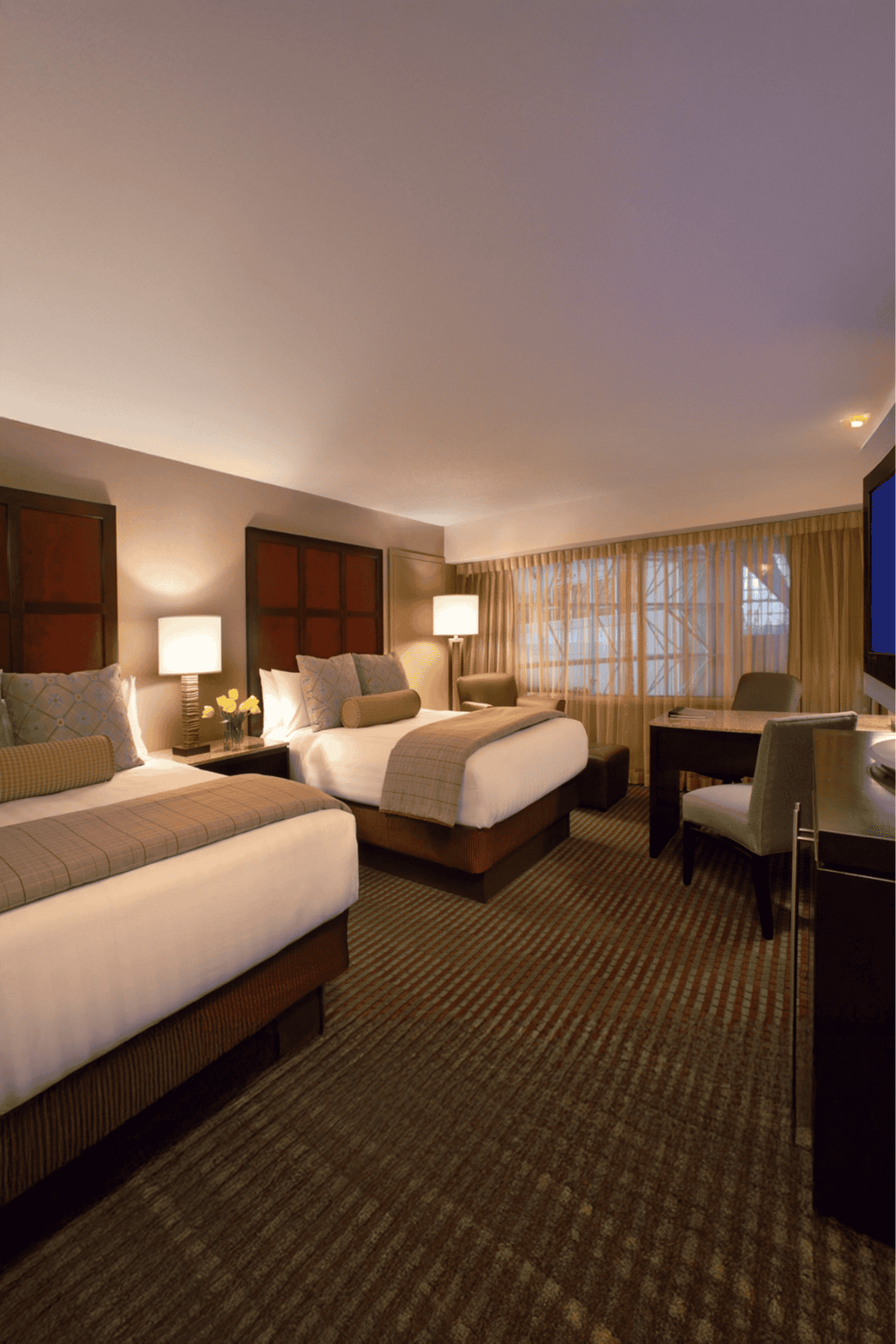 Comfortable hotel room with two beds, modern decor, and workspace for travelers.