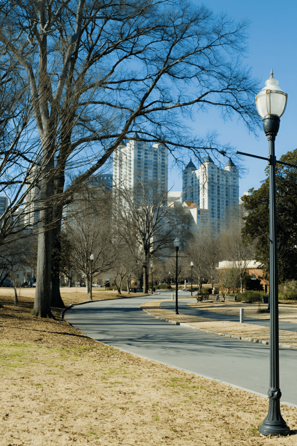City park with urban skyline, walking path, and street lamp in downtown Atlanta, Georgia.