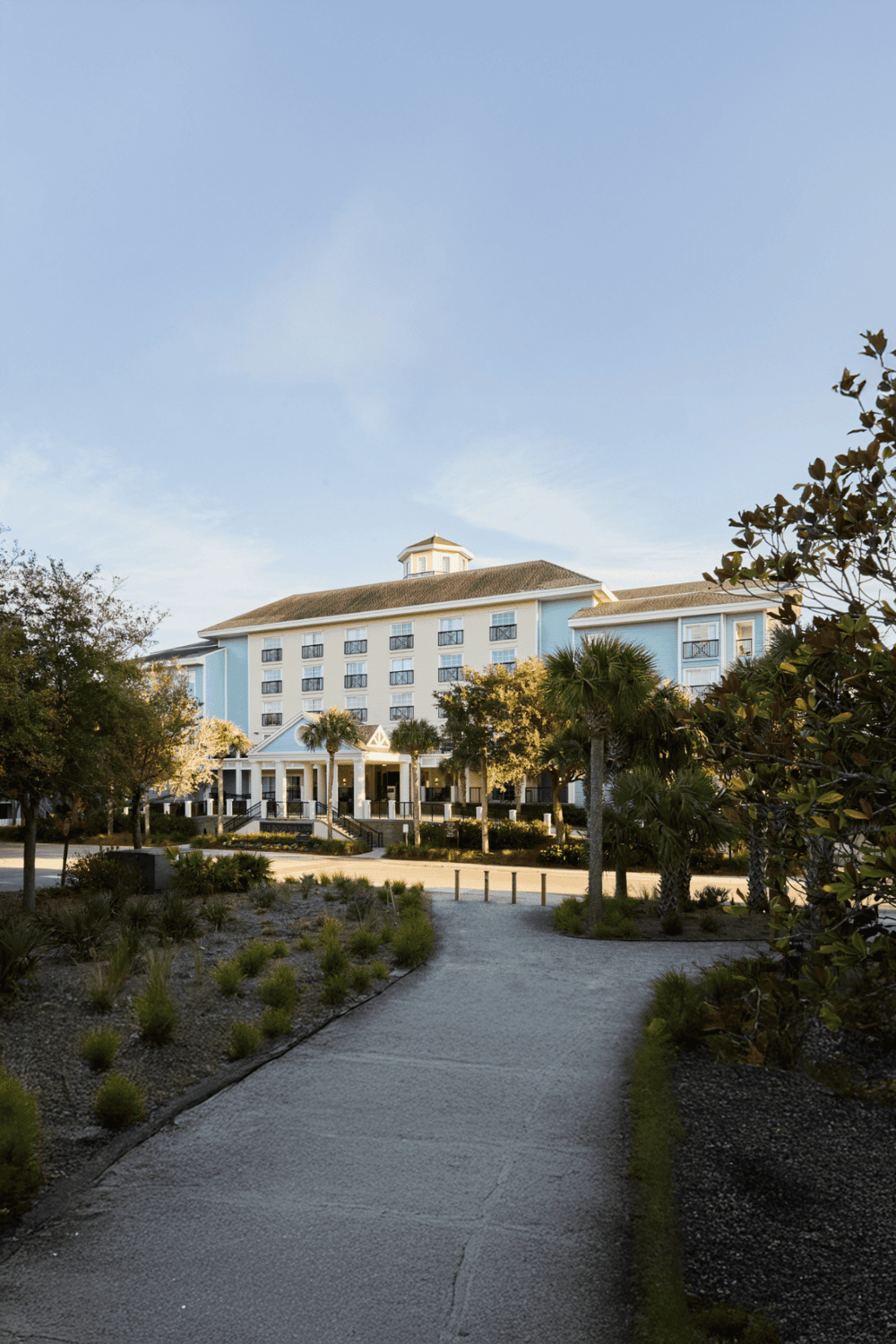 Modern coastal hotel with palm trees and lush landscaping, ideal for vacation stays.