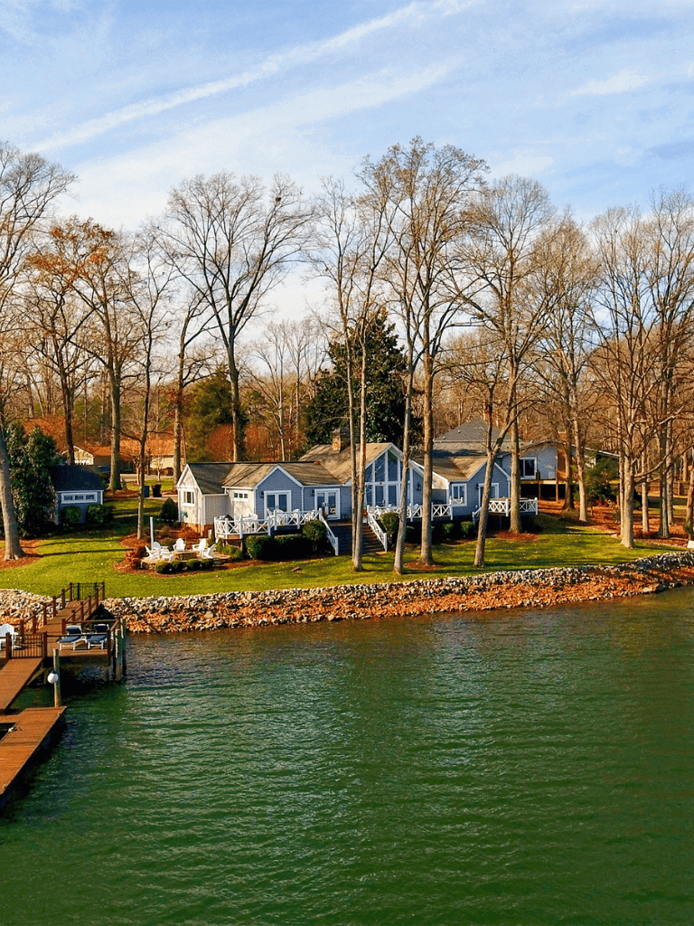 Waterfront house with dock and trees in fall season, scenic lakeside retreat.