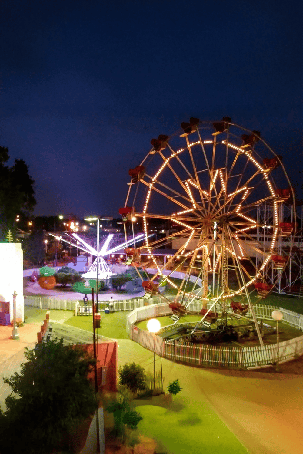 Amusement park Ferris wheel and rides at night, family entertainment, fun attractions, Quest For Directions, travel destination.