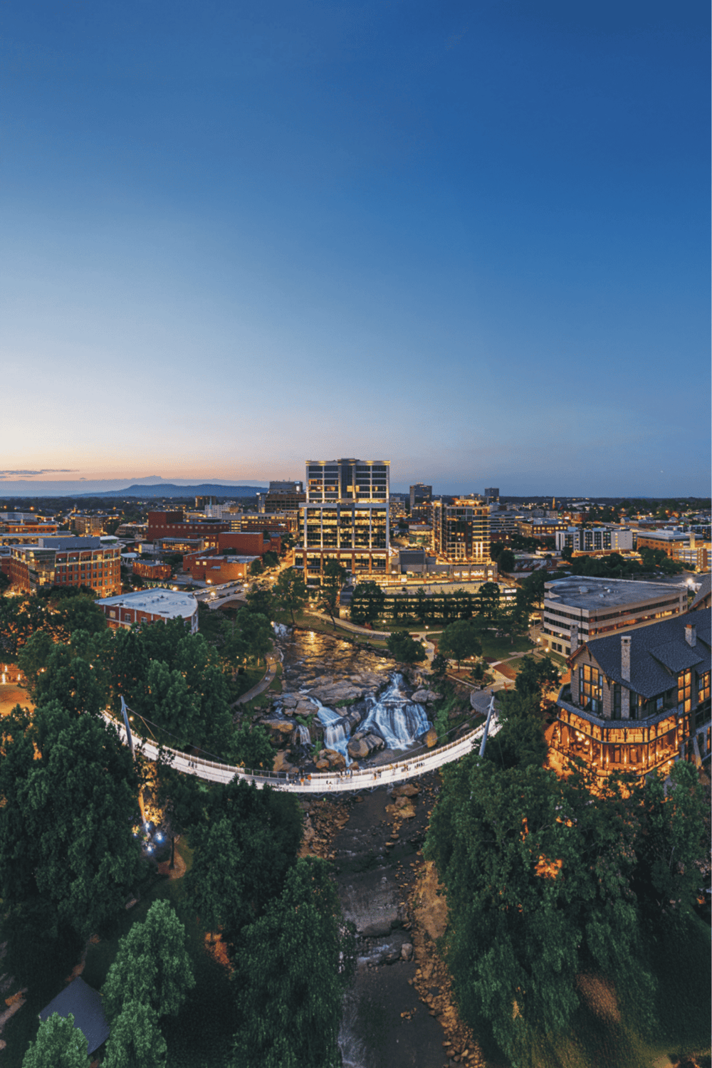 Urban cityscape with scenic waterfall and modern buildings during dusk, highlighting downtown Chattanooga, Tennessee.
