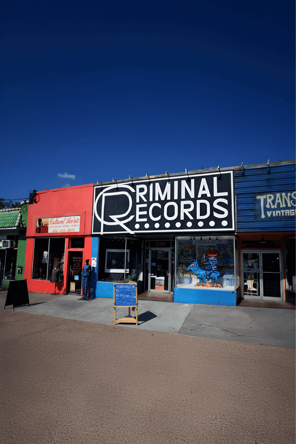 Unique Records store front with bold black and white sign in vibrant shopping district scenery.
