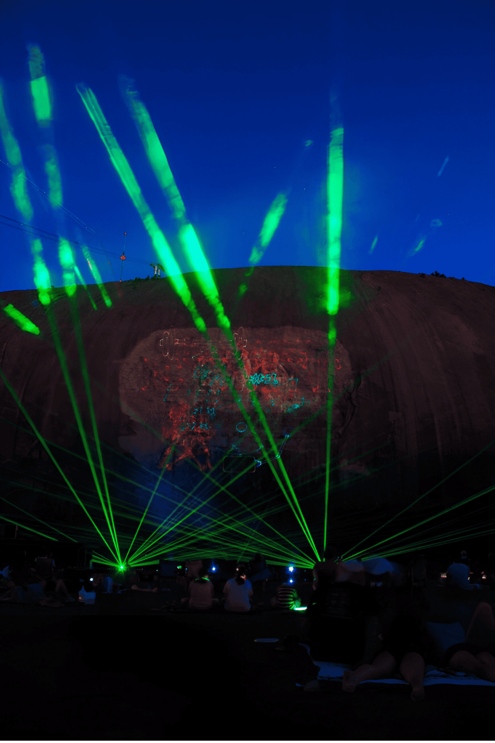 Laser light show at Quest for Directions event, vibrant green lasers illuminate night sky.