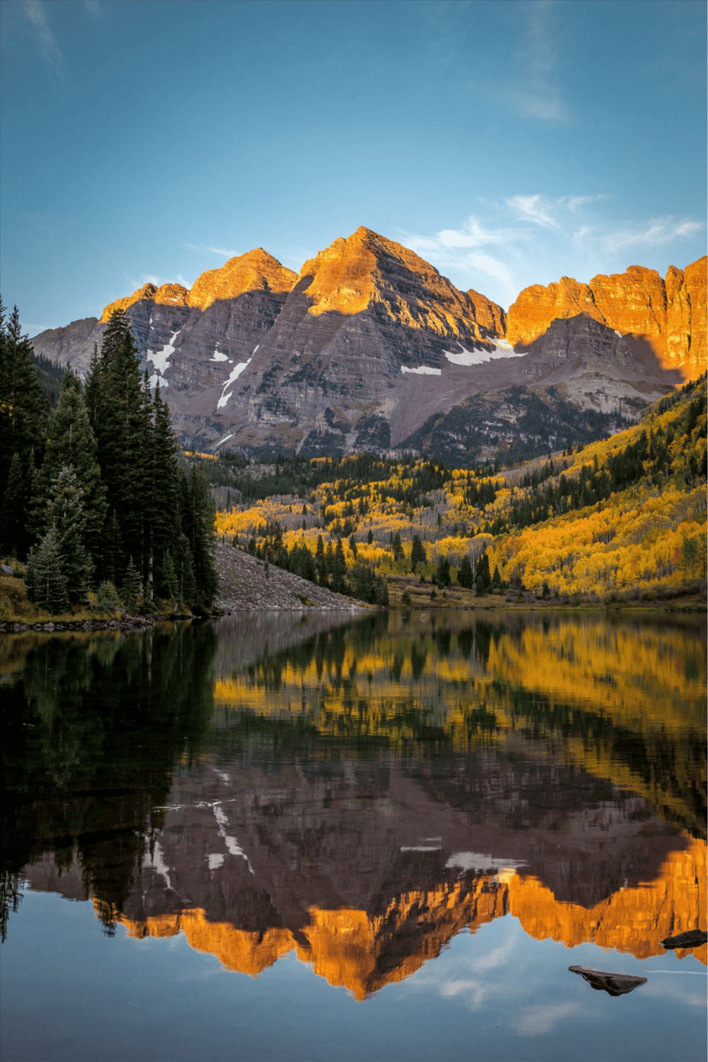 Serene mountain lake with autumn foliage, reflected in clear water, in a national park setting.