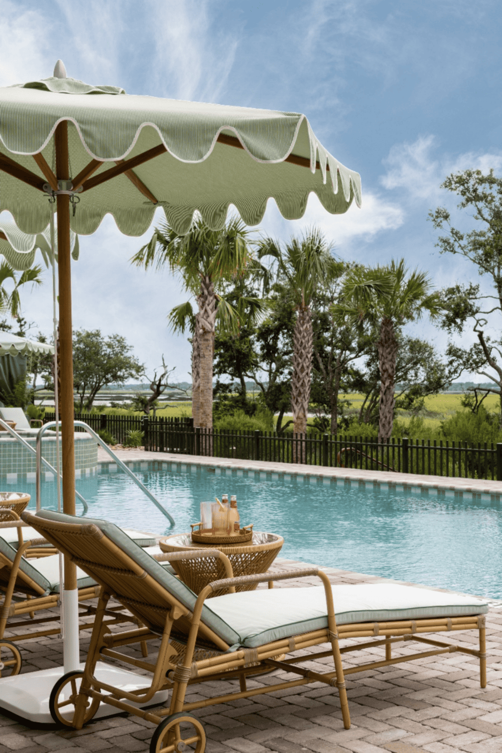Poolside outdoor relaxing area with lounging chairs and umbrella in a tropical setting.