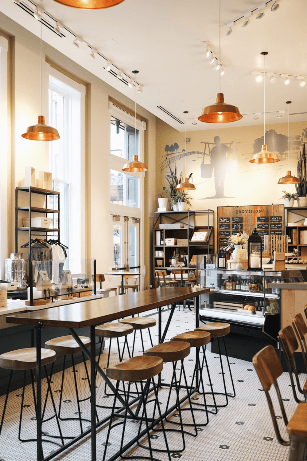 Cozy modern cafe interior with wooden stools, high tables, and warm lighting; inviting space for coffee and socializing.