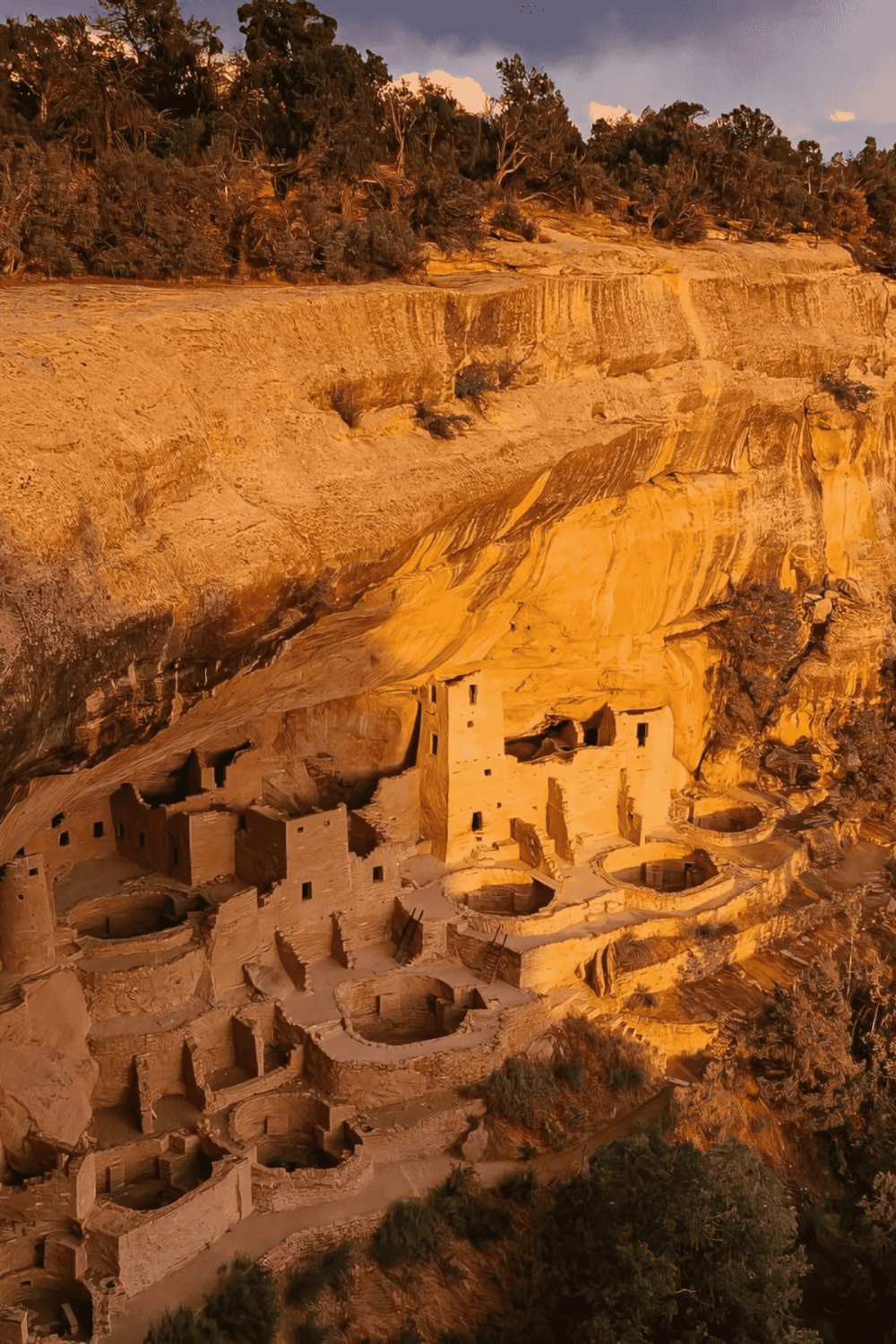 Ancient cliff dwellings of the Ancestral Puebloans nestled in a rugged canyon with volcanic rock formations.