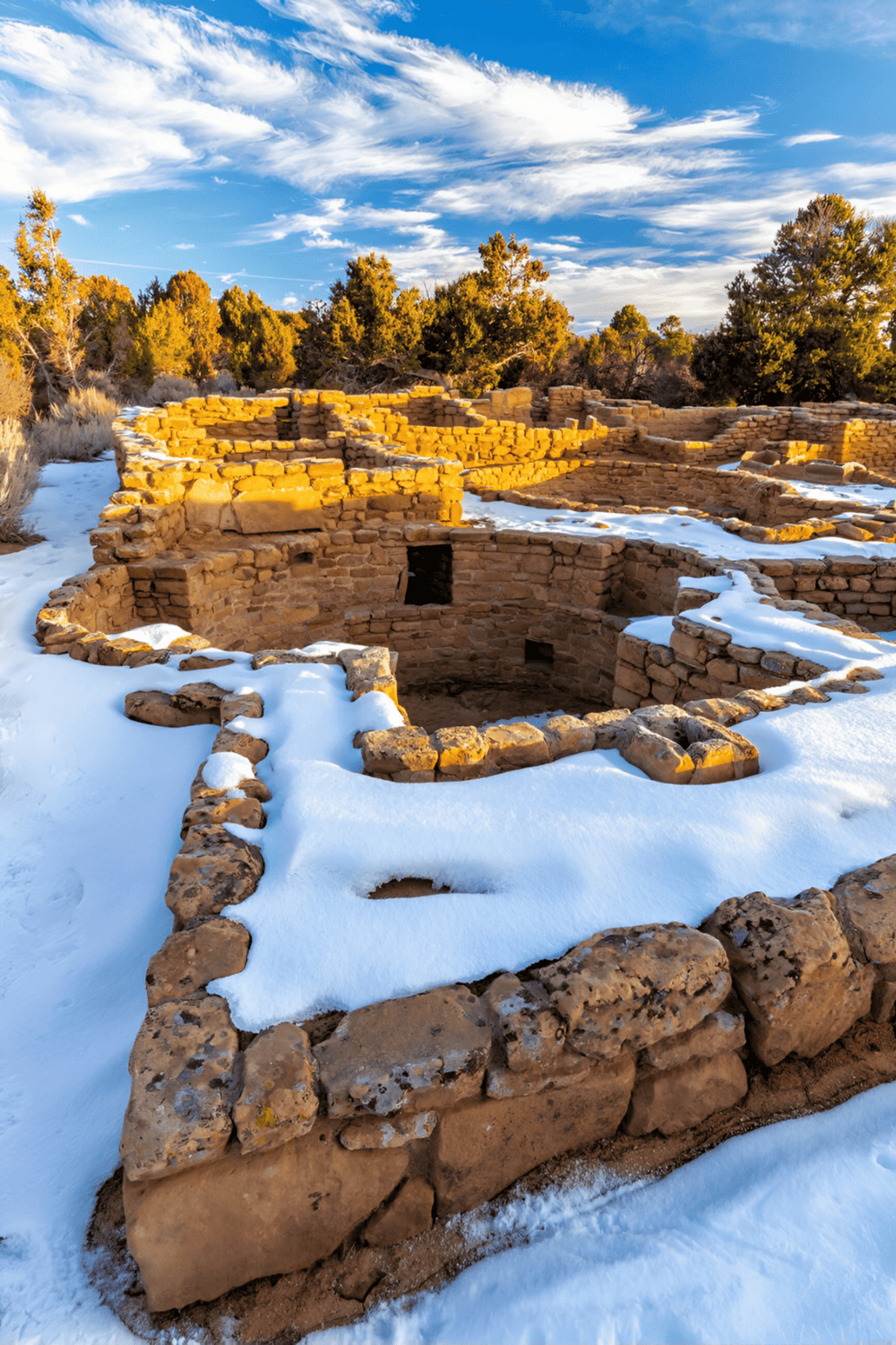 Ancient Ancestral Puebloan ruins in snow, showcasing archaeological sites and Native American history.