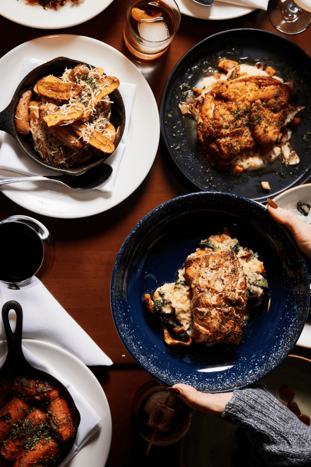 Golden-brown roasted chicken with herbs, creamy mashed potatoes, and vegetables on a dark blue plate.