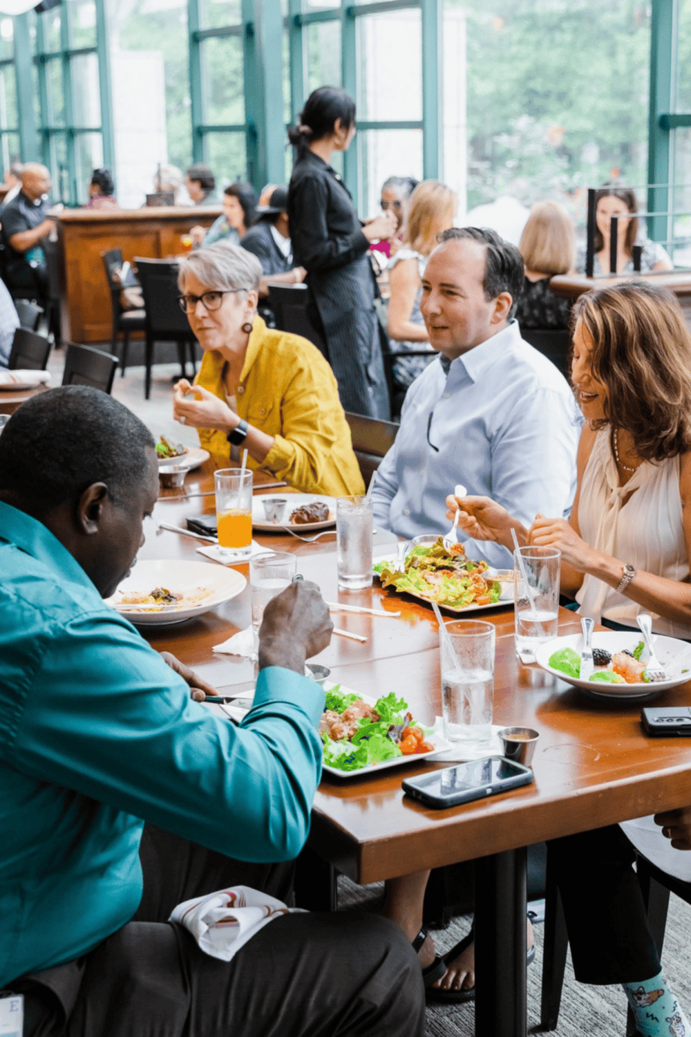 Enjoying a diverse group meal at a modern restaurant with large windows.