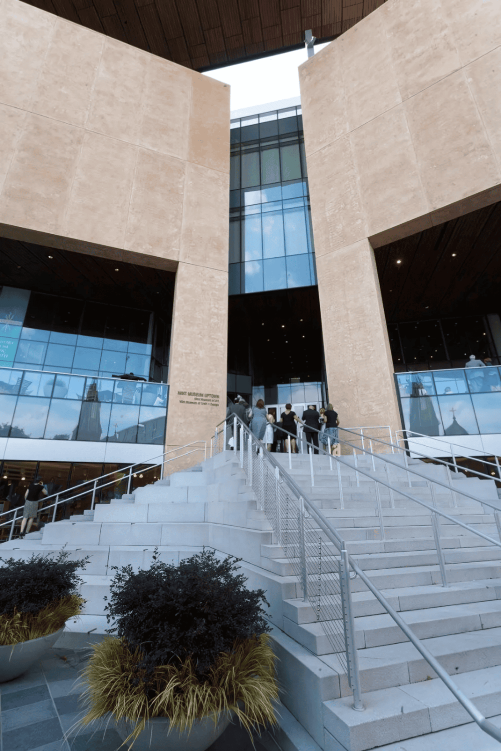 Modern courthouse entrance with glass and stone architectural design, stairs, and visitors.