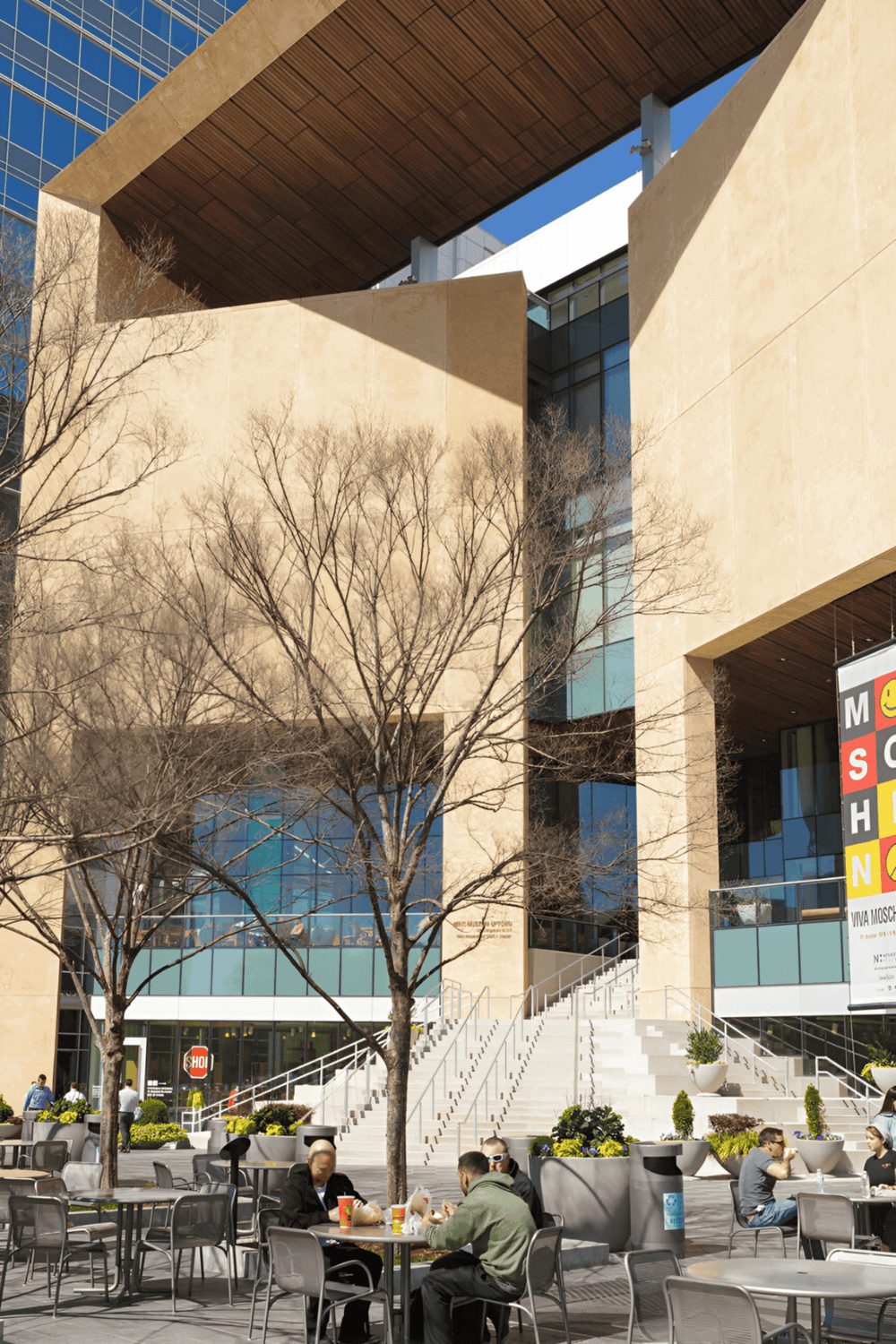 Modern architectural building with outdoor seating area, trees, and stairs at QuestForDirections.