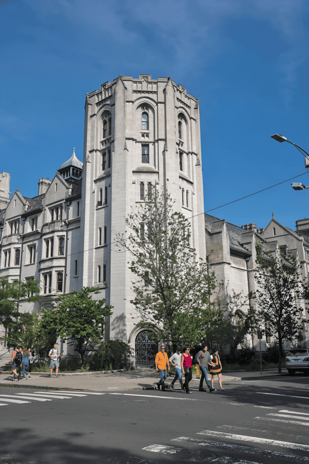 Grand historic building with Gothic architecture and pedestrians crossing street.