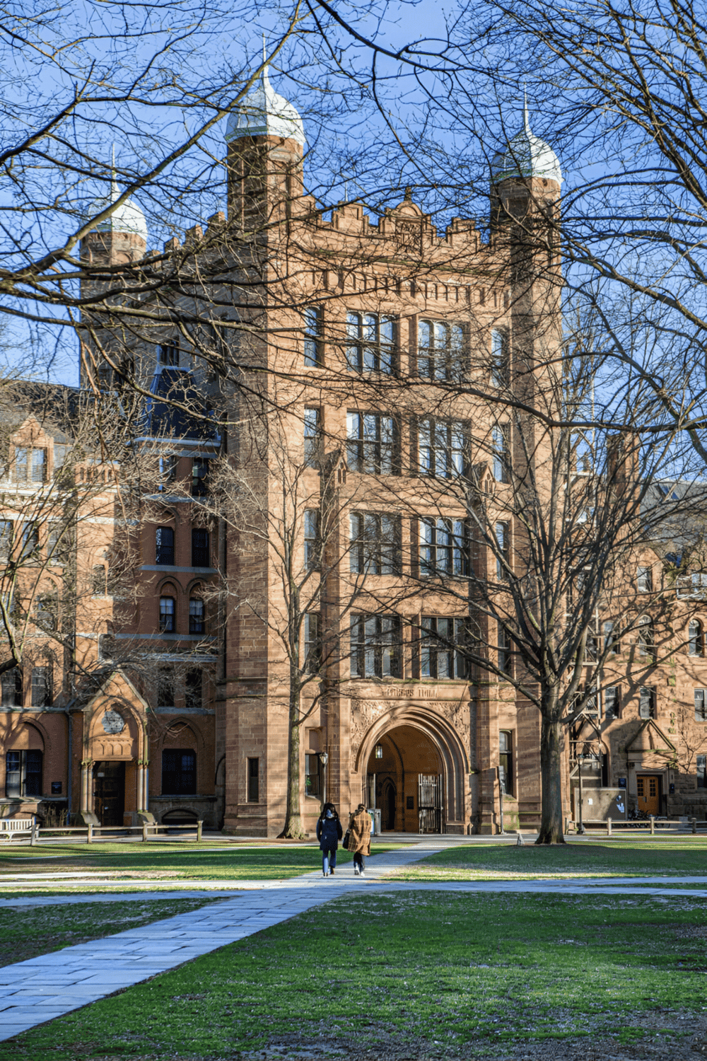 Historic castle with brick walls and towers, surrounded by trees and green lawn.