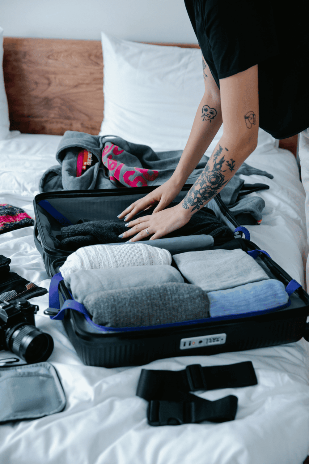 Suitcase packing for travel with clothing, camera, and accessories at home.