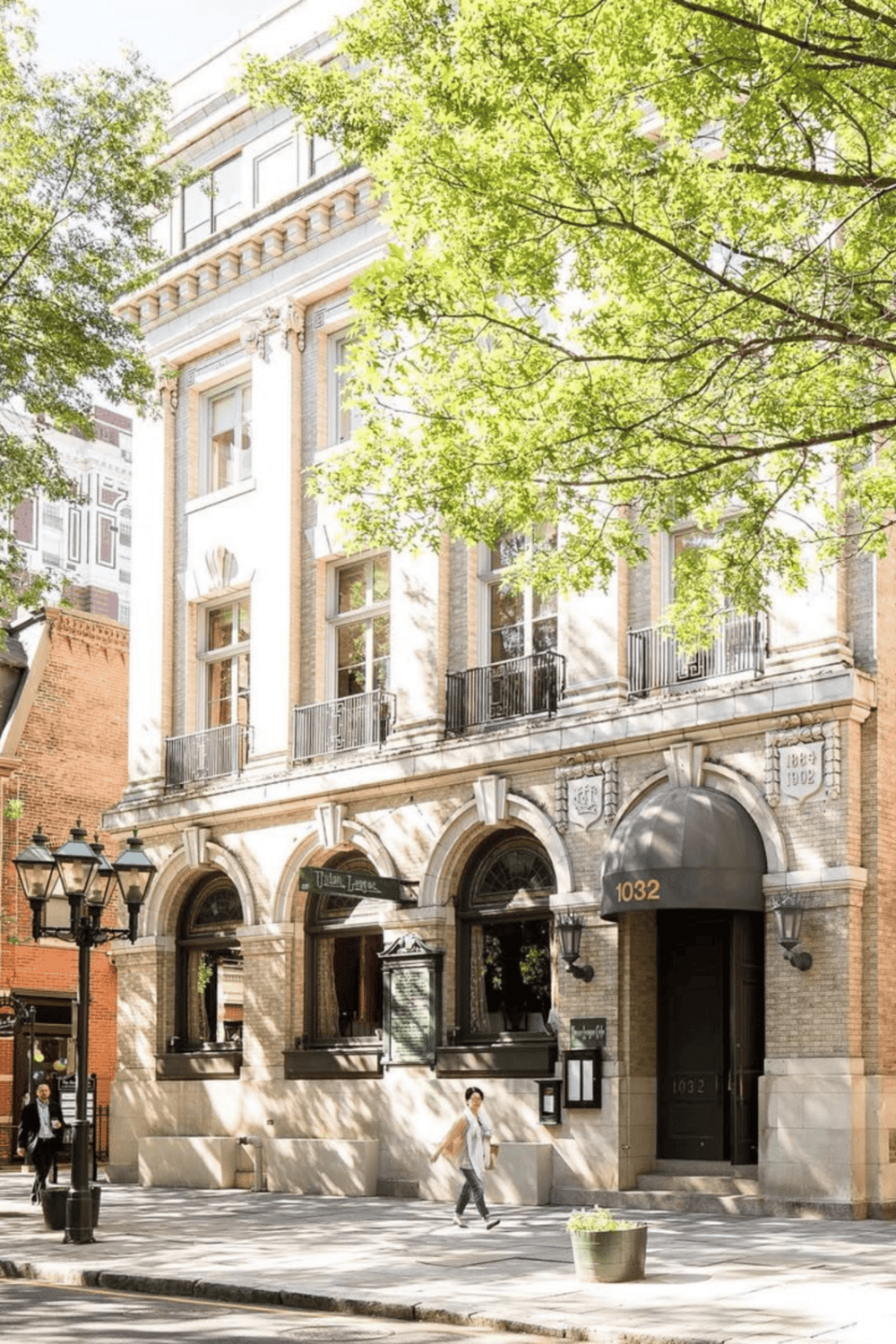 Victorian-style building with ornate architecture and green trees in downtown area.