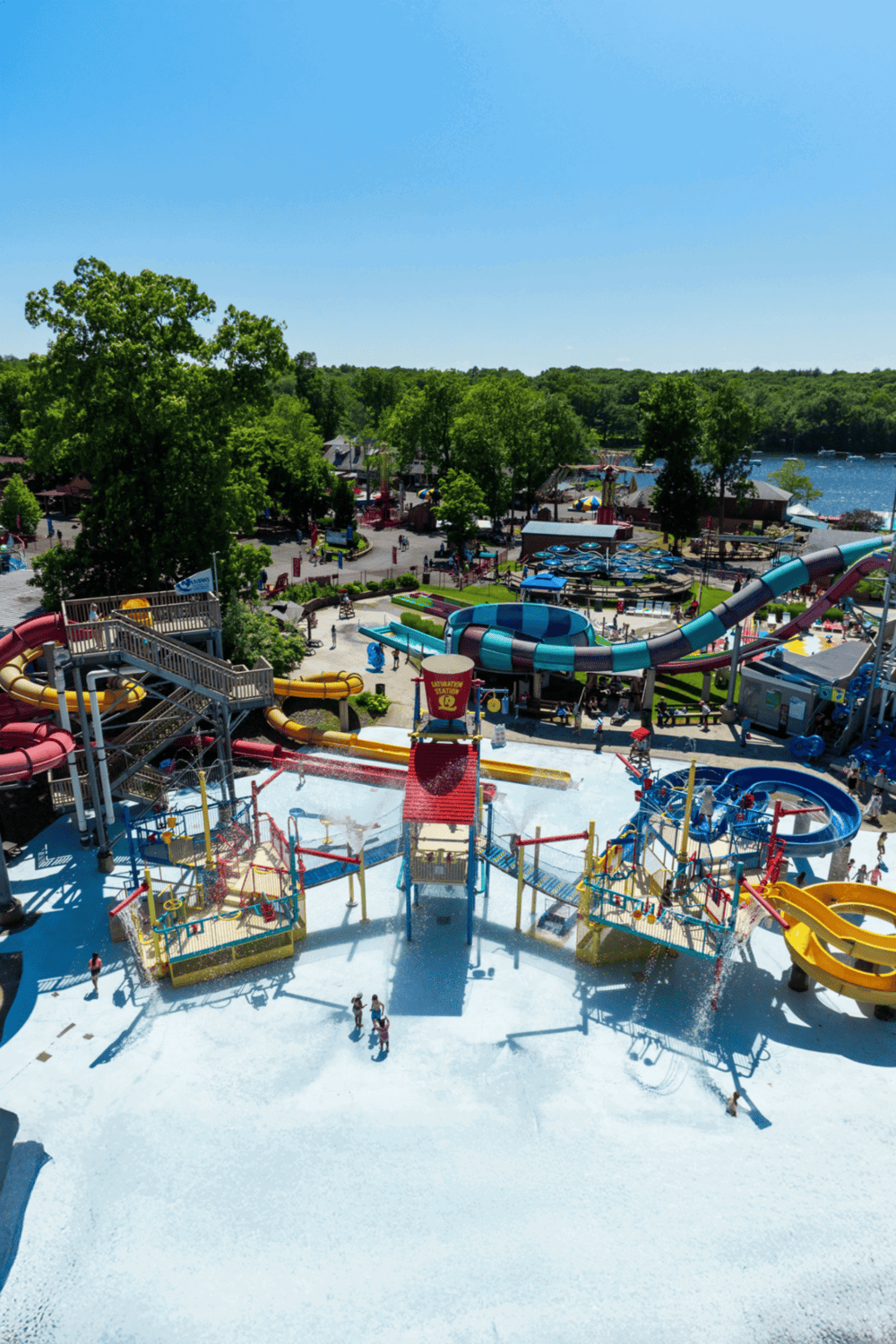 Colorful water park with slides and attractions near a lake, perfect for family fun and outdoor entertainment.