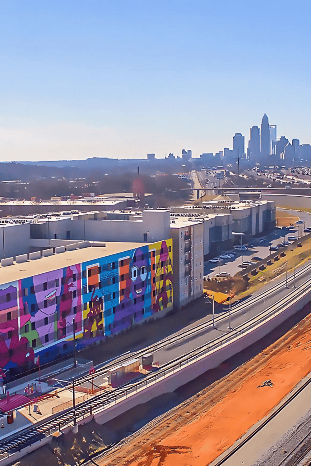 Colorful city mural with downtown skyline in the background, urban landscape, and rail tracks, highlighting QuestForDirections services.
