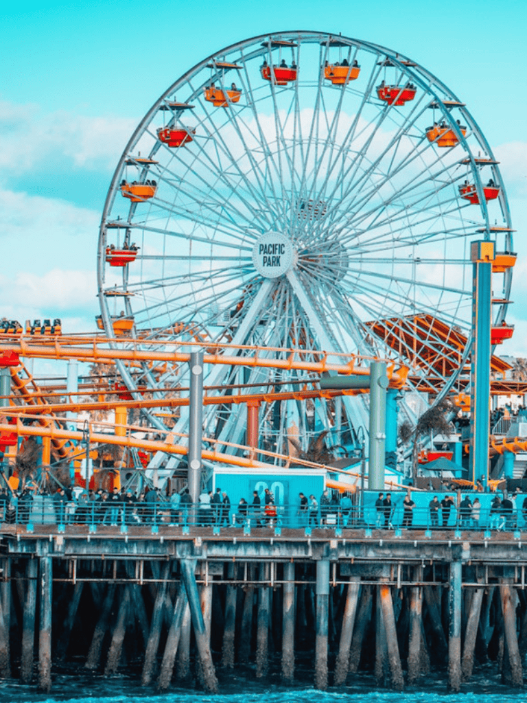 Bright Ferris wheel at Pacific Park on the Santa Monica Pier, California, at sunset.