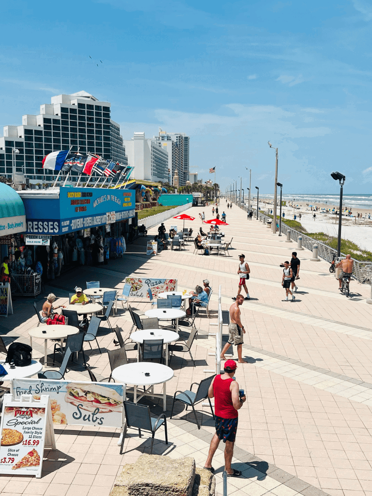 Vibrant seaside promenade with cafes, shops, and beach views in Daytona Beach, Florida.
