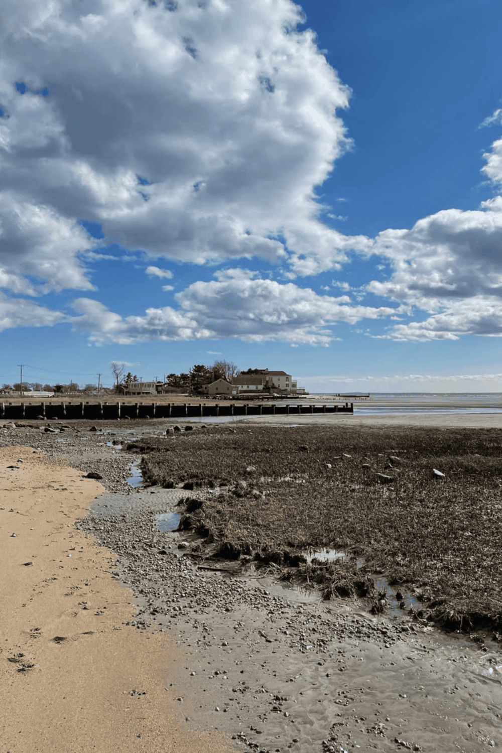 Seaside houses and pier under a cloudy blue sky at QuestForDirections location.