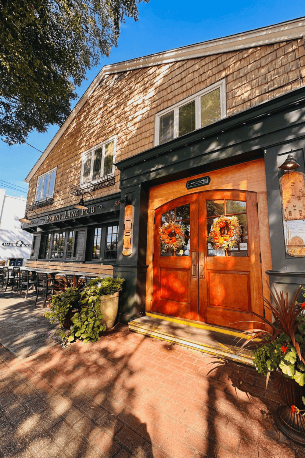 Warm welcoming pub entrance decorated for fall with orange wreaths and outdoor seating, perfect for local dining.