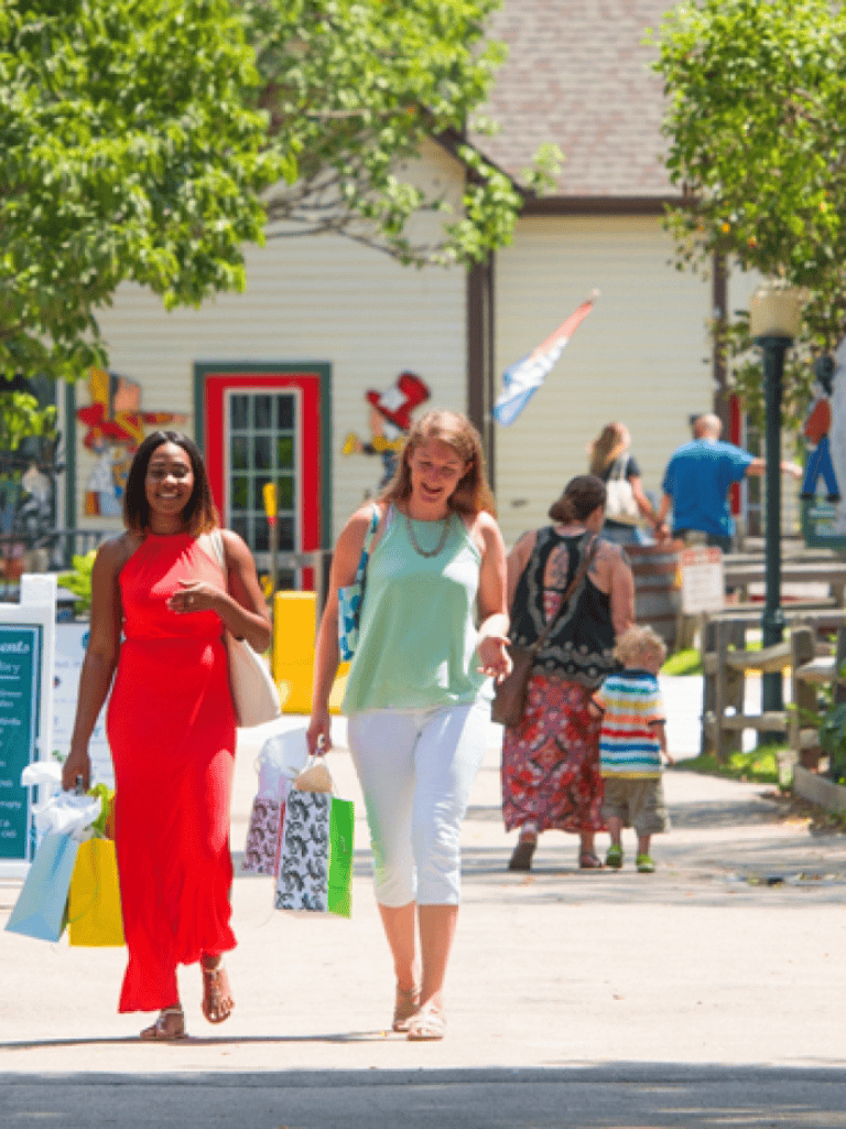 Brightly dressed women shopping at outdoor mall, summer day, retail therapy, fashionable, community shopping.