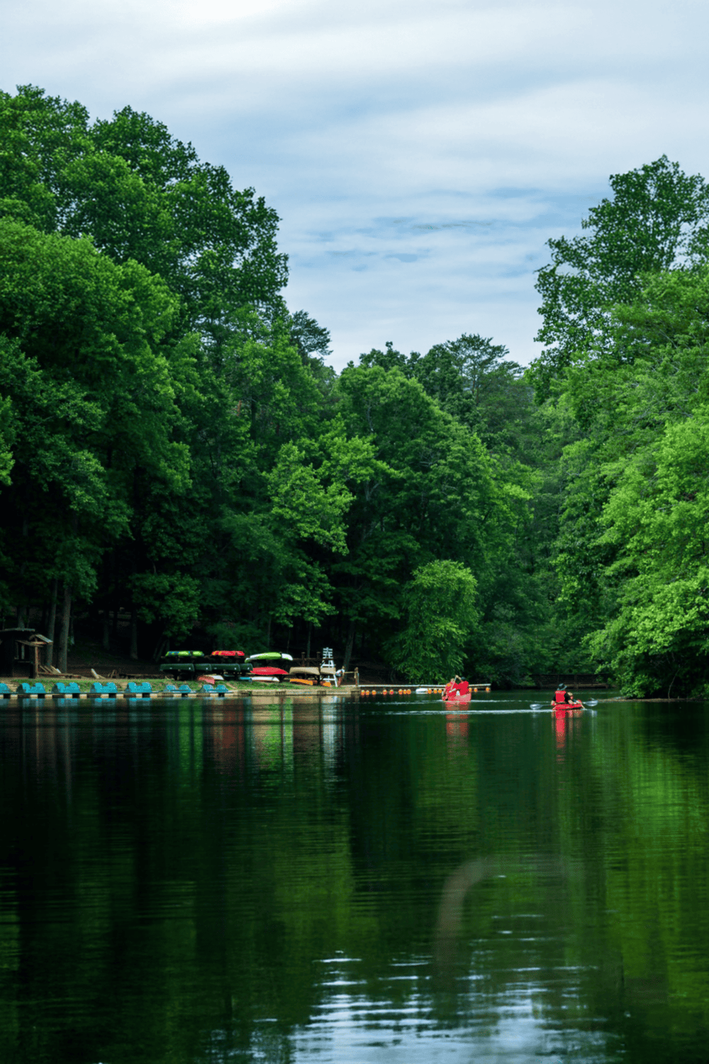 Tranquil river scene with kayaks and lush green trees, ideal for outdoor adventures and nature exploration.