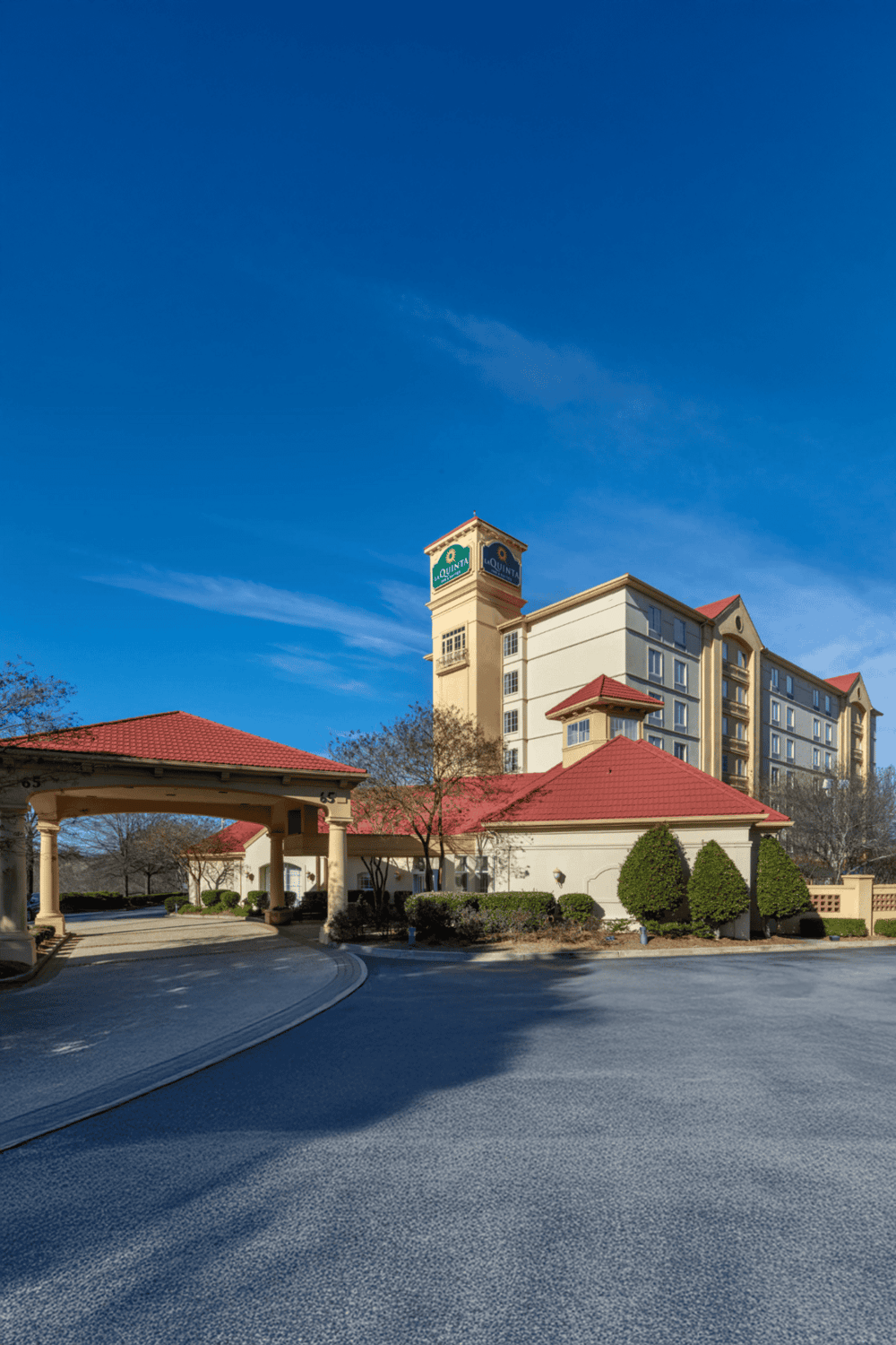 Elegant hotel entrance with lush landscaping and clear blue sky, perfect for travelers seeking luxury accommodations.