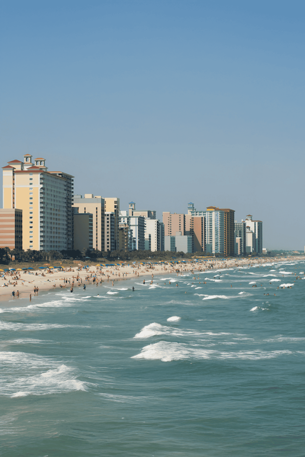 Beachside city skyline with high-rise hotels and a busy sandy shoreline, popular for coastal vacations and tourism.